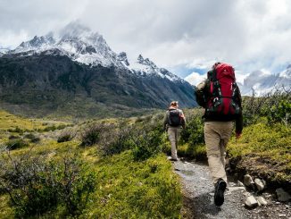 two person walking towards mountain covered with snow